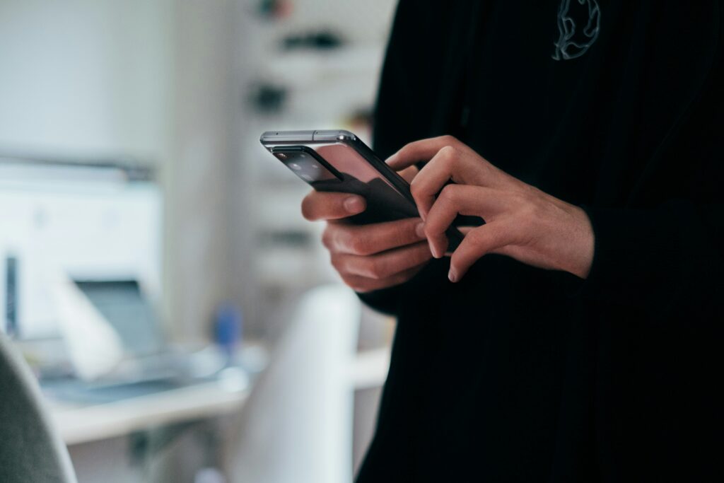 A person holding a smartphone displaying the Pharmaoffer "Sourcing Brief" newsletter. The screen shows the heading "Closing the Response Gap" and the "100% Match or Your Money Back" guarantee, emphasizing a mobile-friendly, expert-led procurement process